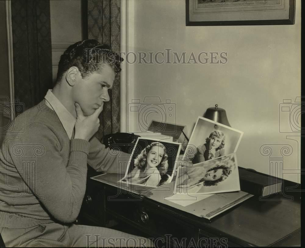 1941 Press Photo Actor Jackie Cooper looks at pictures of beautiful women.