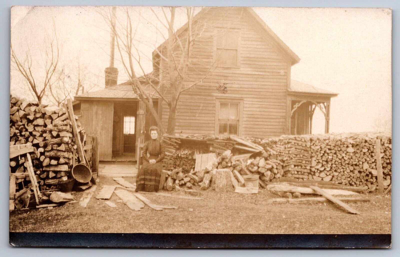 RPPC Lovely Lady Posing Outside Farmhouse Stacked Wood Victorian Era Postcard