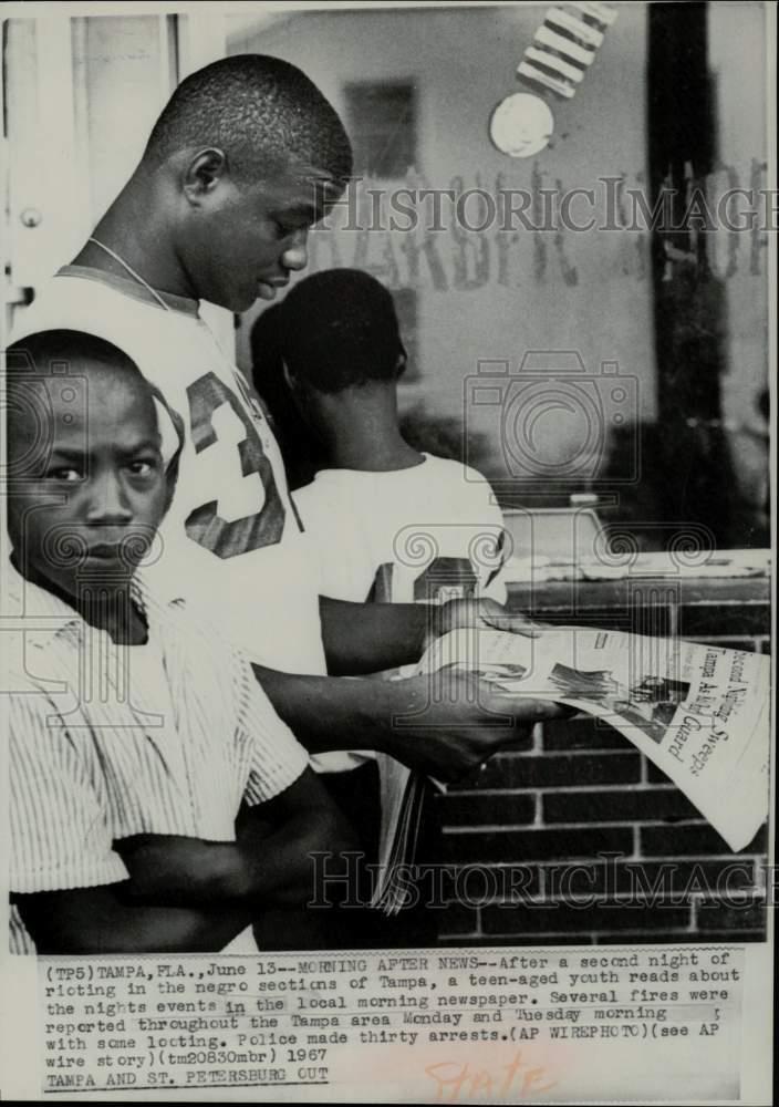 1967 Press Photo A Teenager reads newspaper reports on riots in Tampa, FL