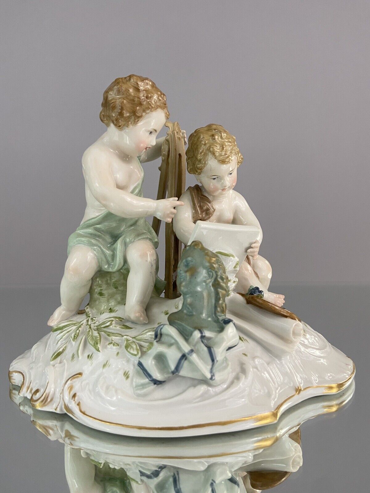 Antique Kpm figurine depicting cherubs with easel & painting subject. Meissen