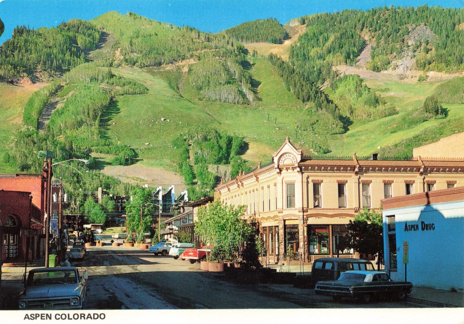 Postcard CO Aspen Mountain Rocky Mountains Cars Drug Store Street View Ski Trail