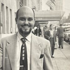 smiling bald man in suit goatee walking down street snapshot photograph picture