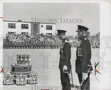 1959 Press Photo Two officials view stack of drums at ceremony in Great Britain picture