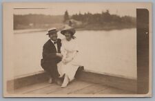 Smiling Couple Sitting On Dock With Water View Behind RPPC Real Photo Postcard picture