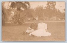 RPPC Couple Dressed Fashionably Sits in Grass AZO1904-1918 ANTIQUE Postcard 1358 picture