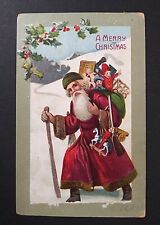 A Merry Christmas Santa in Green Hat Toys in Snow Embossed Postcard c1910s picture