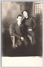 RPPC Smiling Couple Sitting On Chair In Studio c1910 Real Photo Postcard picture