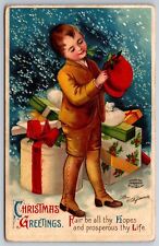 Ellen H Clapsaddle Christmas~Boy w/Holly In Teeth Adorns Red Hat~Gifts~Snow~1910 picture